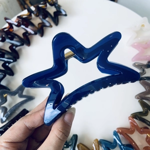Macro detail of a navy blue star-shaped hollow hair claw with a gold metal spring