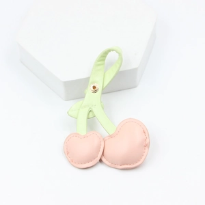 Detail shot of pink and light green cherry-shaped leather keychain with metal snap clasp