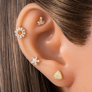 Set of four gold titanium piercing studs featuring star, crown, and geometric shapes
