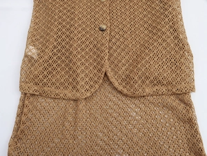 Detailed close-up of brown knit mesh fabric texture with dark buttons on a beach top