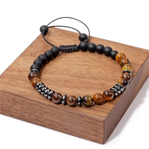 Tiger eye and matte black bead woven bracelet with adjustable cord on wood base