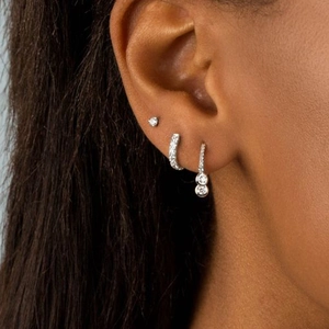 Close-up of triple earring set featuring silver hoops and studs with cubic zirconia