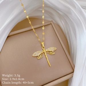 Detailed close-up of a gold dragonfly pendant necklace with white zircons on silk