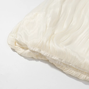 Detailed macro view of cream mercerized fabric with elegant vertical pleated textures