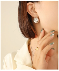 Polished silver U-shape geometric ball earrings worn by model with minimalist cream blazer