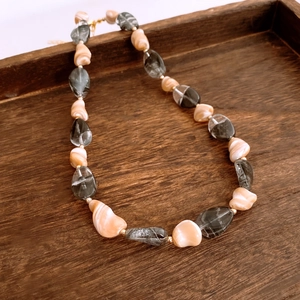 Détail macro de perles irrégulières et d'entretoises dorées sur un collier rétro