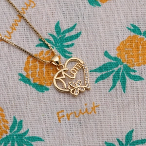 Detailansicht der goldenen Herz-Halskette mit Mom-Schriftzug und Schmetterling