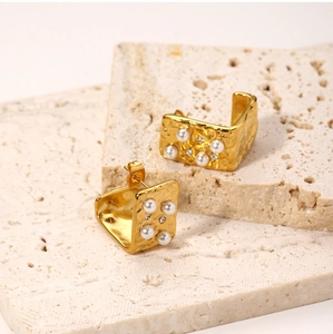 Detail of 18K gold stainless steel earrings with textured finish and pearls on stones