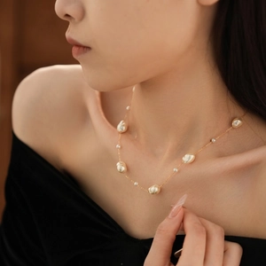 Baroque pearl necklace with gold-plated chain worn by a model in a French vintage style