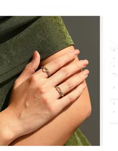 Detail of gold chain-link rings with pavé heart and rectangle charms on hand