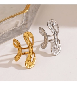 Detail of minimalist gold and silver hammered rings on a warm beige background