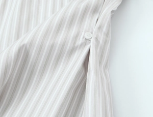 Close-up of gray striped cotton shirt showing delicate side seam and white button detail