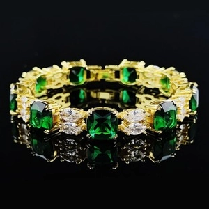 Detail of emerald green square stone and marquise diamond tennis bracelet in gold