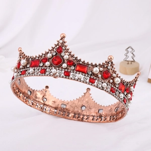 Close-up of vintage gold Baroque crown with red gemstones and white pearls on fabric