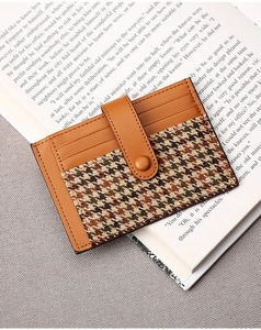 Detail view of caramel leather and houndstooth card holder on an open book