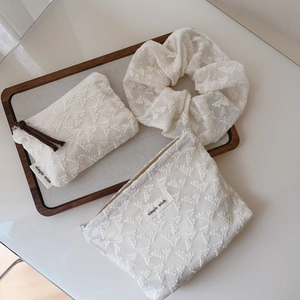 Three-piece beige lace set with floral embroidery including pouches and a scrunchie