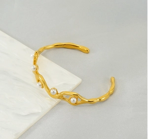 Detail of 18K gold-plated wavy cuff bracelet featuring five elegant white pearls