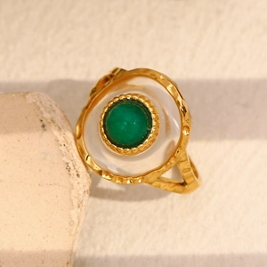 Detailed close-up of 18K gold-plated ring with green emerald stone and hammered metal finish
