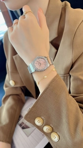 Close-up of elegant women's watch with pink dial, crystal bezel and silver band