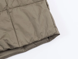Detailed close-up of quilted stitching and hem texture on dark khaki winter jacket