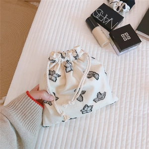 Detail of a minimalist linen drawstring pouch with black butterfly print for cosmetics