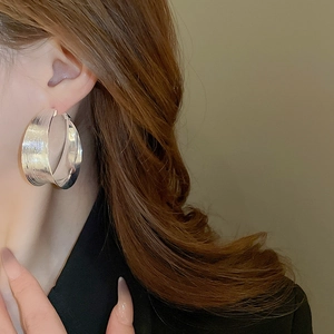 Close-up of silver textured hoop earring on model showing sleek brushed metal detail