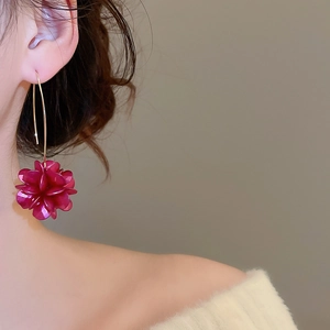 Dettaglio di eleganti orecchini a fiore rosso rosa con ganci dorati su una modella