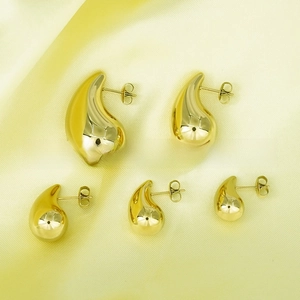 Macro view of five sizes of 18K gold-plated teardrop stud earrings on yellow silk