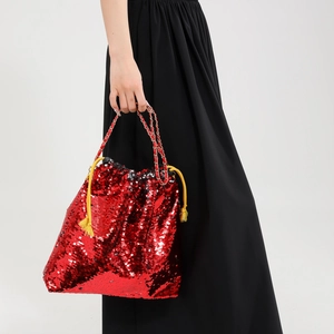 Detail of red sequin bucket bag with yellow drawstrings and metallic chain strap