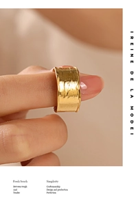 Macro view of wide gold-colored ring with hammered texture on model hand