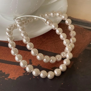 Minimalist 925 sterling silver pearl necklace with metallic accents on a white cup