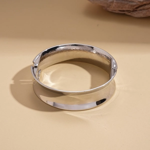 Detailed view of wide silver metal cuff bracelet on natural wood background