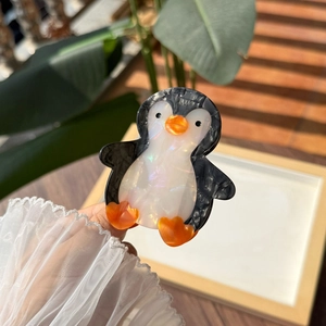 Dettaglio del fermaglio per capelli in acetato a forma di pinguino con finitura perlata lucida