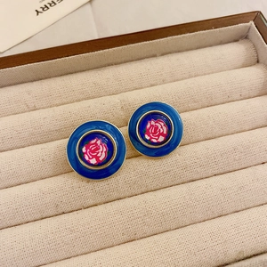 Détail macro de boucles d'oreilles vintage émaillées bleues avec rose rose sur velours