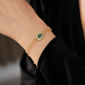 Close-up of vintage gold bracelet featuring oval emerald green zircon and intricate metalwork