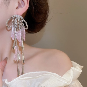 Close-up of sparkling bow tassel earrings with crystals and soft pink leaf details