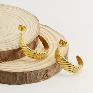 Detailed view of 18K gold titanium steel hoop earrings with shell texture on wood slices
