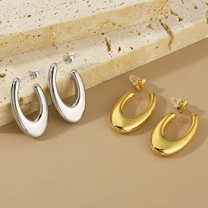 Detail of minimalist U-shaped hoop earrings in gold and silver finish on stone