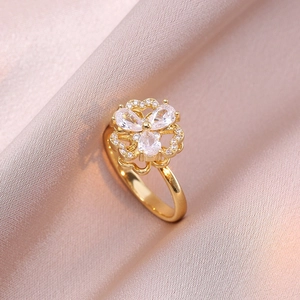 Rotating four-leaf clover ring in gold finish with micro-set zircon on silk background
