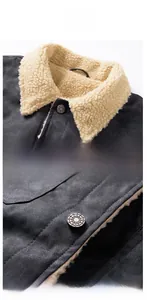 Detail der Winterjacke mit beigem Lammfellkragen und Metallknöpfen mit Spinnennetzmuster