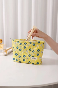 Close-up of yellow floral quilted makeup bag featuring smooth metal zipper and soft cotton fabric