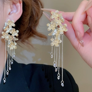 Detailed close-up of golden floral butterfly tassel earrings with crystal pendants