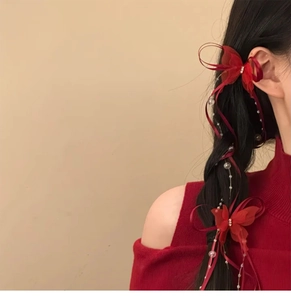 Detail of red ribbon bow hair clip with white pearls on a long braided hairstyle