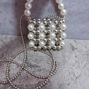 Detail of beaded mini bag with white pearls and silver metal beads in grid pattern