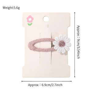 Detail view of a daisy flower hair clip showing 5.6g weight and size on display card