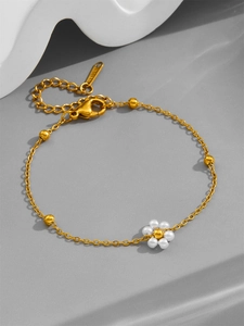 Detail of gold stainless steel flower bracelet with white pearls and small round beads