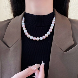 Close-up of multicolored pearl necklace layered over a black turtleneck and brown blazer