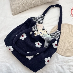 Detail of embroidered floral patterns on navy blue fuzzy tote with checkered lining