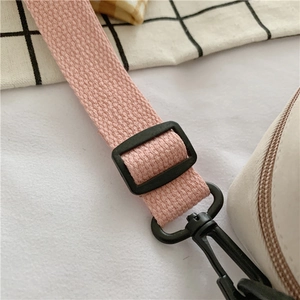 Detail of pink woven strap with black adjustable buckle and swivel clasp on white bag