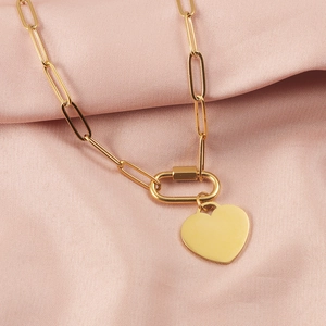 Close-up of golden paperclip chain necklace with a heart pendant on pink silk